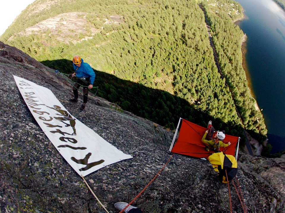 To klatrere på en fjellvegg med utsikt over skog.
