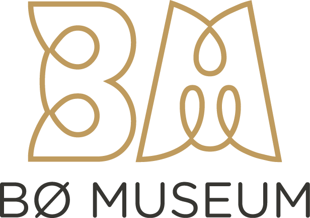 Alt-tekst: Logo for Bø Museum, med stilisert tekst i gull og sort som representerer museets identitet.