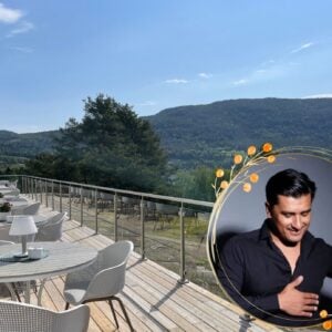 Utsikt fra en terrasse med bord og stoler, vakkert landskap bak og en person som smiler i hjørnet.
